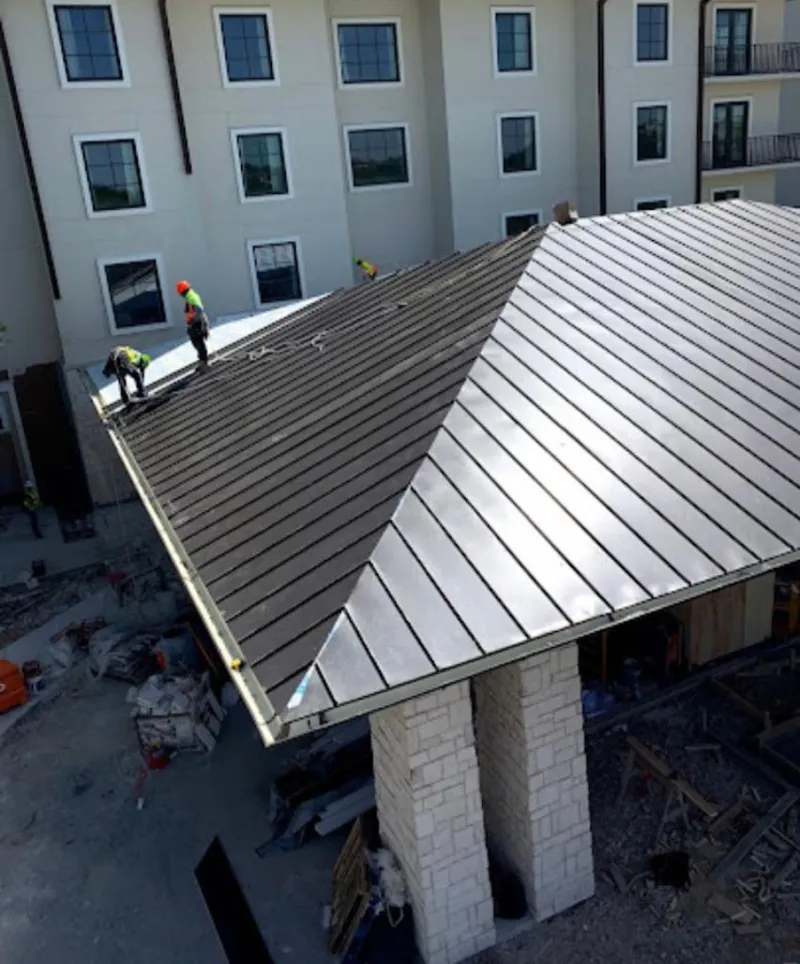 Crew installing standing seam metal roof panels on a commercial project in Cartersville